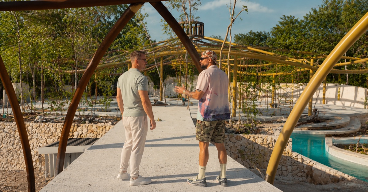 AI-generated image of Craig Jones and Dave Foran talking on a concrete walkway inside the half-built Zamaya resort, the bamboo training pavilion and jungle behind them